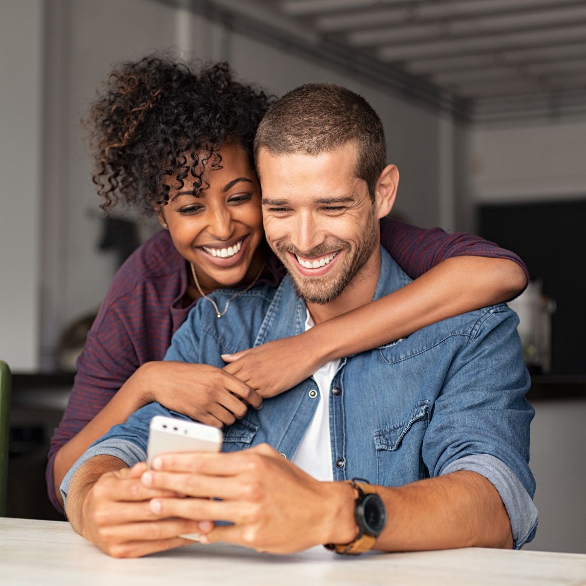 Dos personas que sonríen mientras miran un teléfono